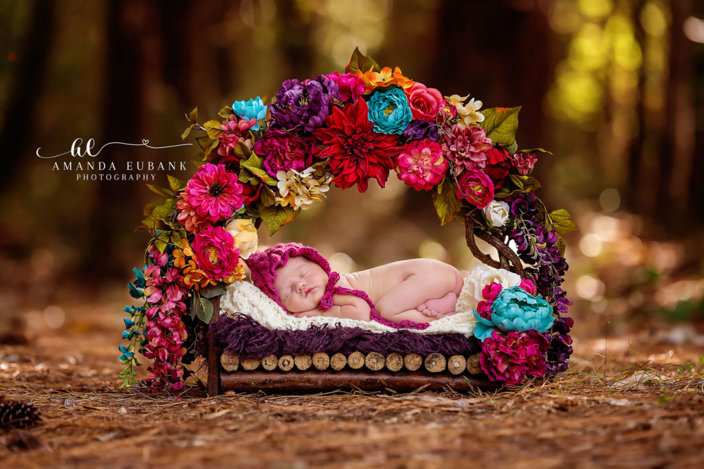 Santa Rosa Beach newborn portrait — profile view inside the pine-forest floral bower; photographed by Amanda Eubank Photography along Florida’s Emerald Coast.