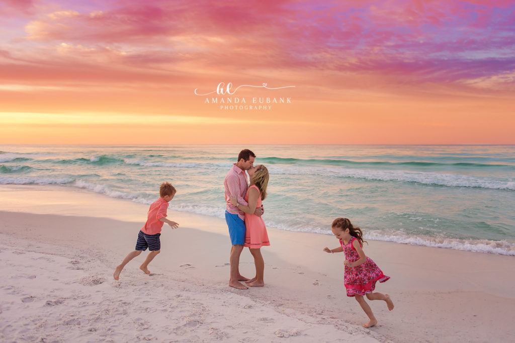 Young girl in floral dress jumping in the surf on Destin Florida beach at twilight — hands out celebration pose