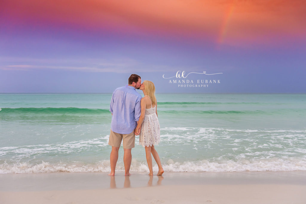 Mary and Reed on the Santa Rosa Beach shore beneath a dramatic purple and orange sunrise sky after the rain.