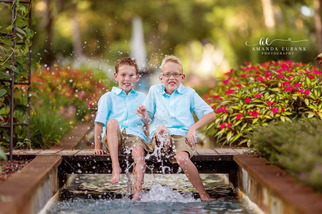 Brady and Brody laughing and splashing barefoot in the Watercolor coastal-garden fountain.