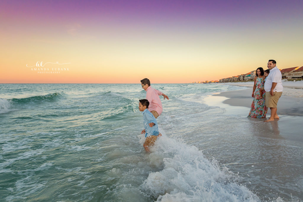 Destin family photographer sunrise beach session — family of four with two young sons walking the Destin, Florida shoreline at sunrise, closing portrait