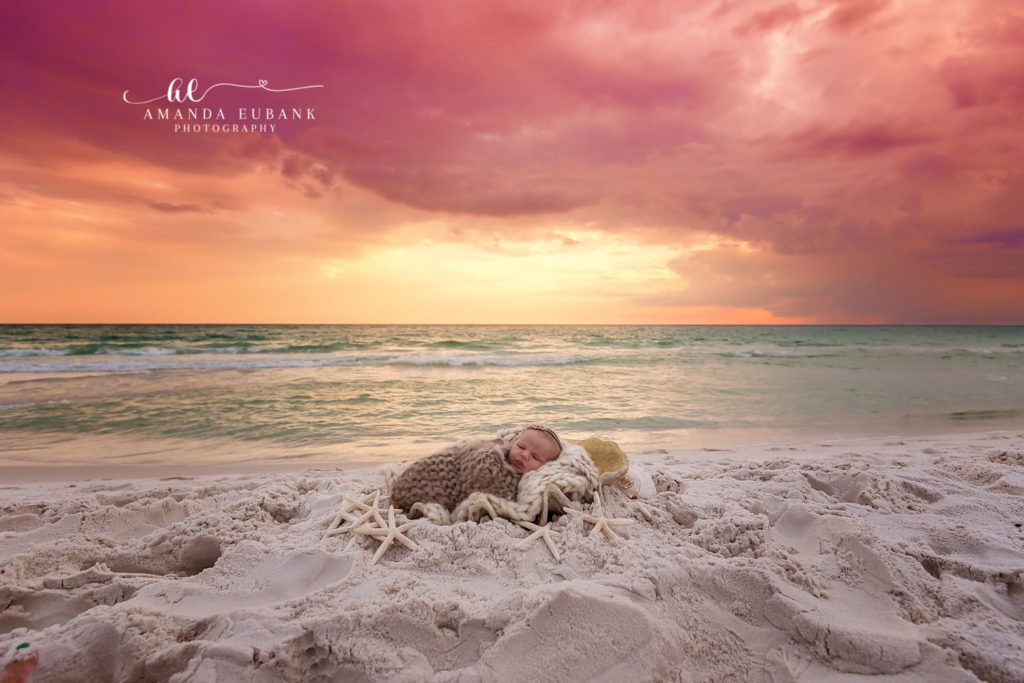 Sweet portrait of newborn Savannah peacefully resting between her parents on the Destin shoreline.