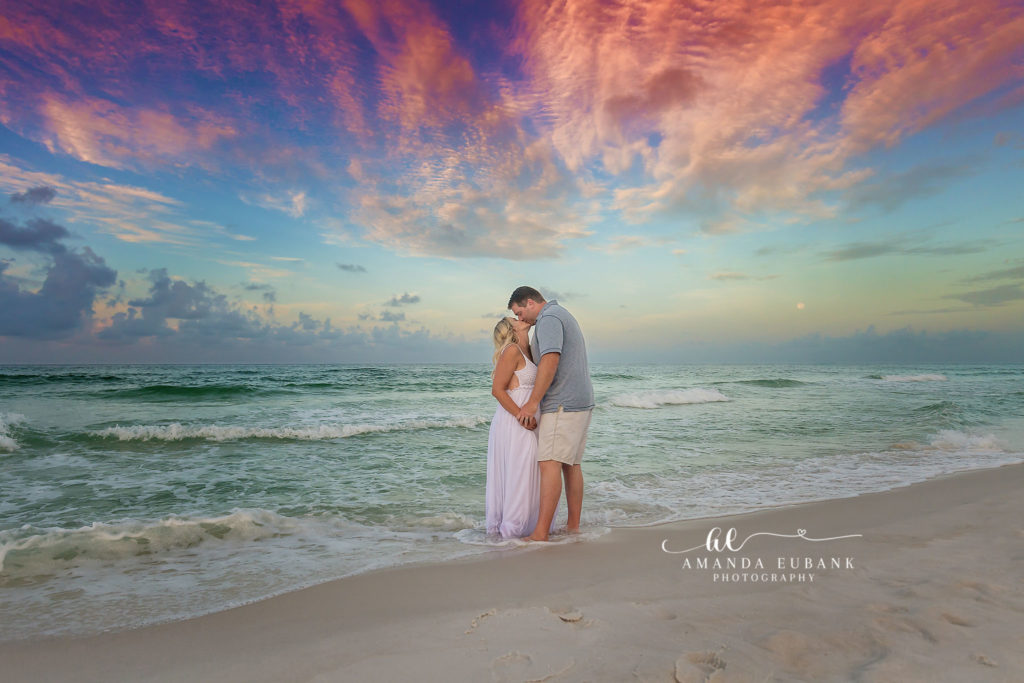 Watercolor Beach maternity photographer portraits Florida expecting couple kissing on beach at vibrant sunset