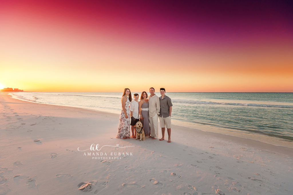 an editorial vertical with the couple framed by sunset stripes during a Destin Beach couple sunset session on Destin Beach beneath a pink-and-amber sunset, photographed by Amanda Eubank Photography