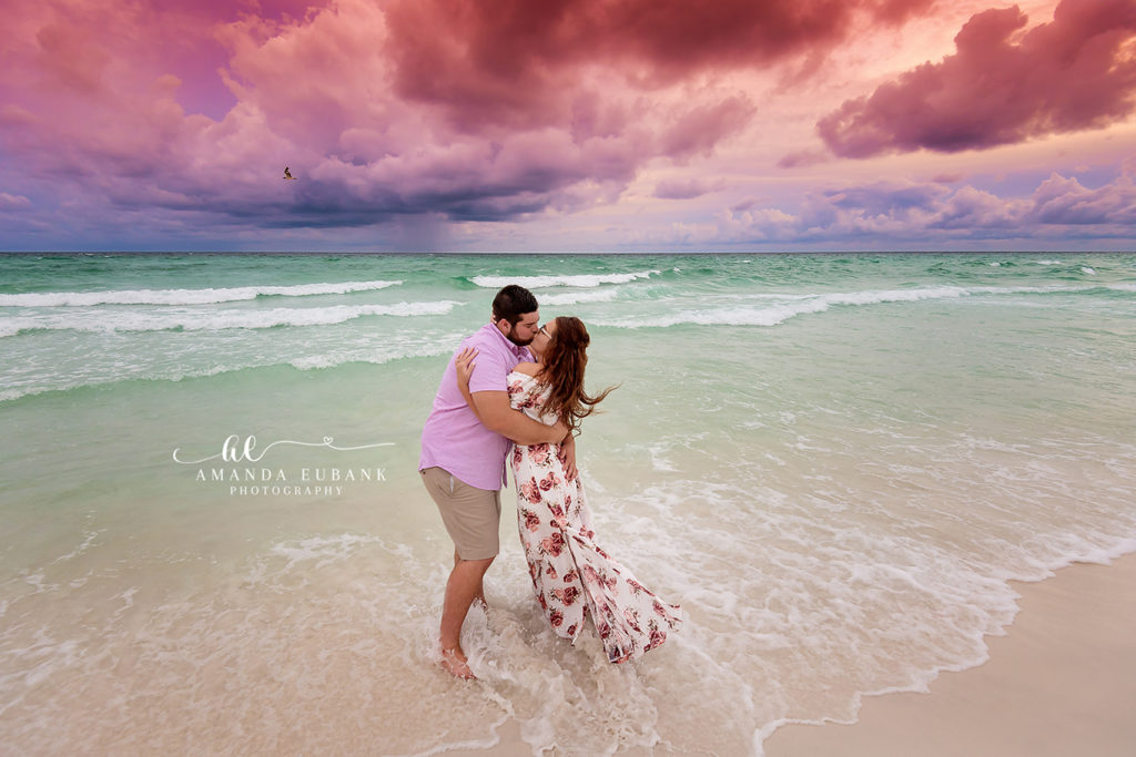 Wrapped in laughter engagement photograph of an engagement-ring focus close-up beside the gulf during a Destin Beach session beneath a cotton-candy clouds