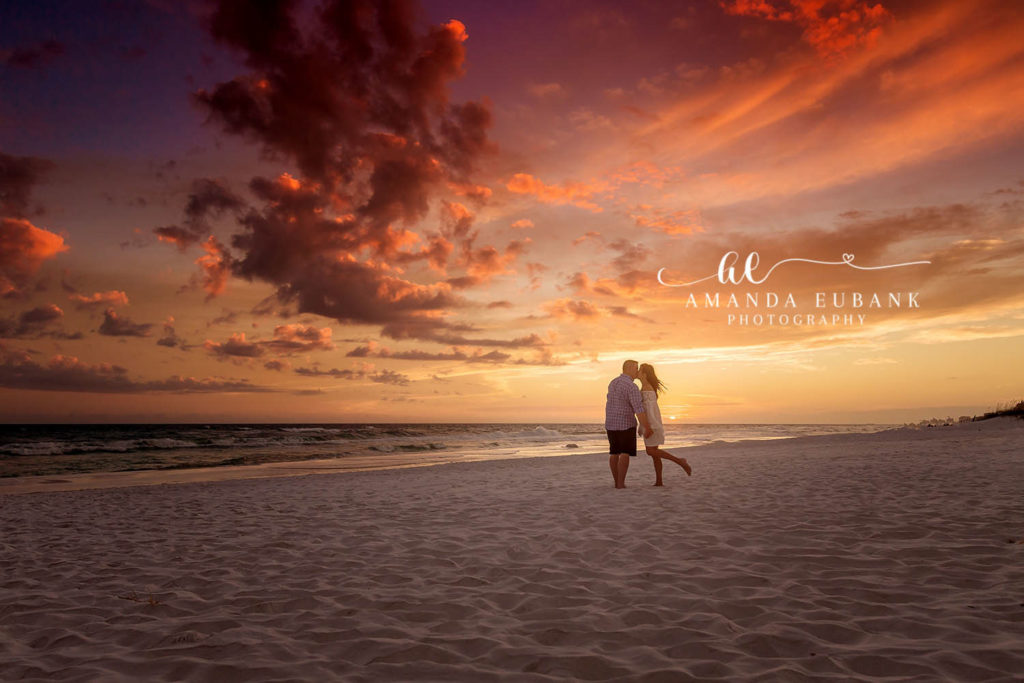 30A Florida engagement photographer captures couple silhouetted on beach against vibrant red orange sunset