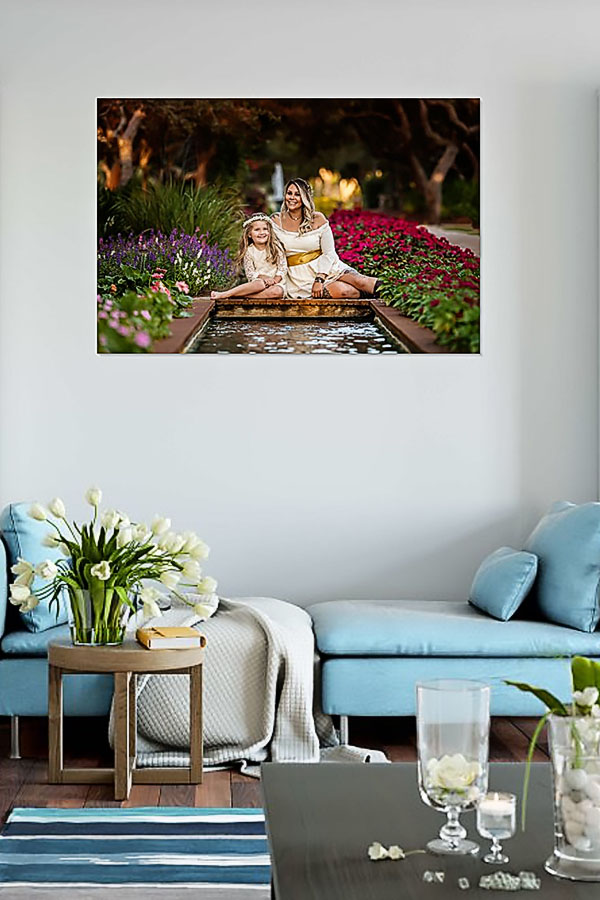 Miramar Beach Florida Family Photographer — Framed Family Portrait Wall Art in Coastal Living Room Framed family portrait of a mom and daughter in white displayed as wall art above a coastal blue sofa in a Miramar Beach, Florida home.
