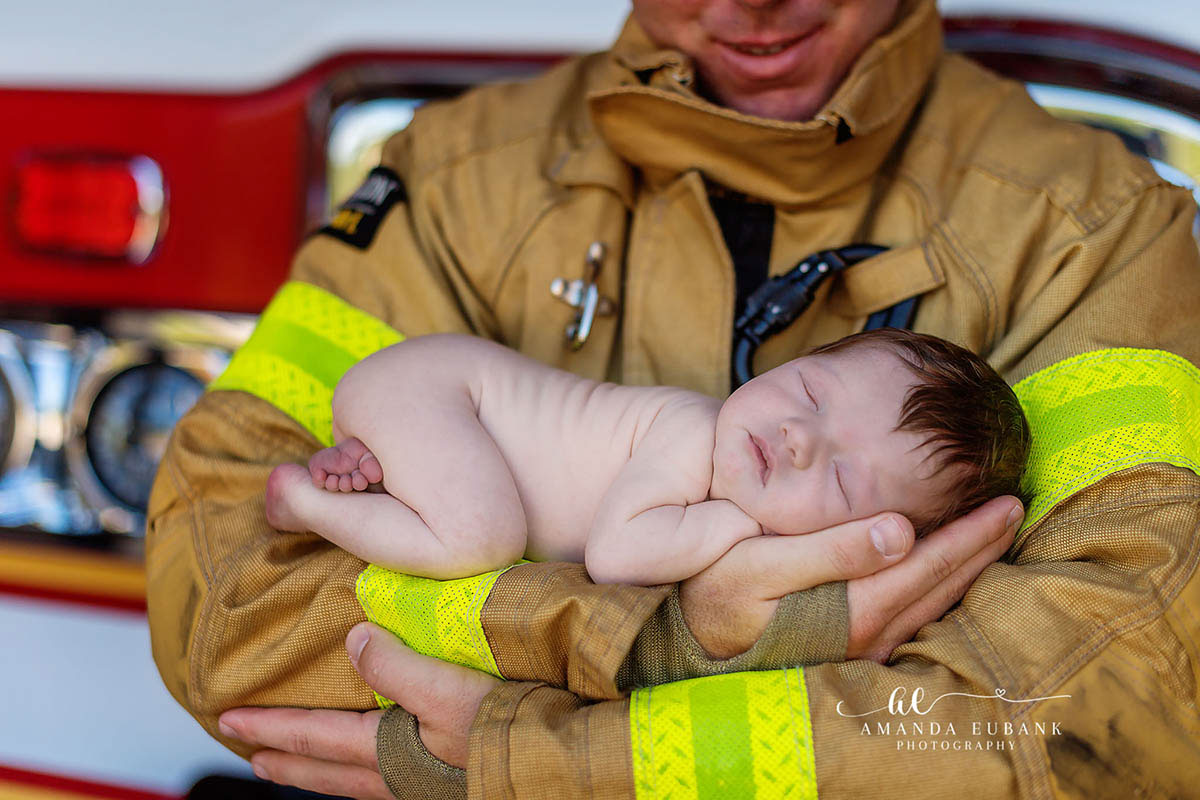 Blue Mountain Beach Florida Newborn Photographer | 30A Firefighter Themed Newborn Blue Mountain Beach Florida newborn photographer captures firefighter dad holding sleeping newborn by fire truck