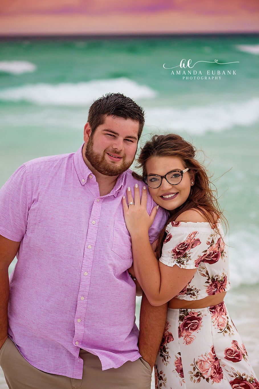Blue Mountain Beach Florida Engagement Photographer — Couple by the Turquoise Gulf Engaged couple posed by the turquoise Gulf with the bride-to-be showing her ring on her fiancé's chest in Blue Mountain Beach, Florida.
