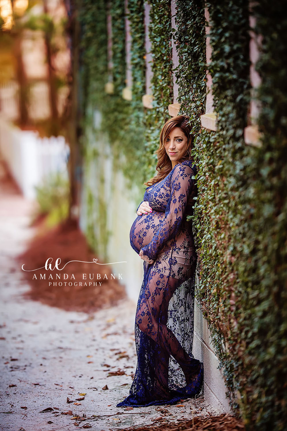 MATERNITY PHOTOGRAPHERS IN MIRAMAR BEACH FLORIDA Maternity photographers in Miramar Beach Florida capture redhead mom-to-be in navy lace gown against ivy wall