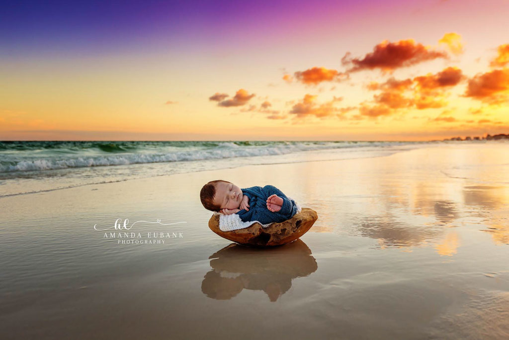 Miramar Beach Florida newborn photographer captures baby in navy wrap in wooden bowl on beach at sunset