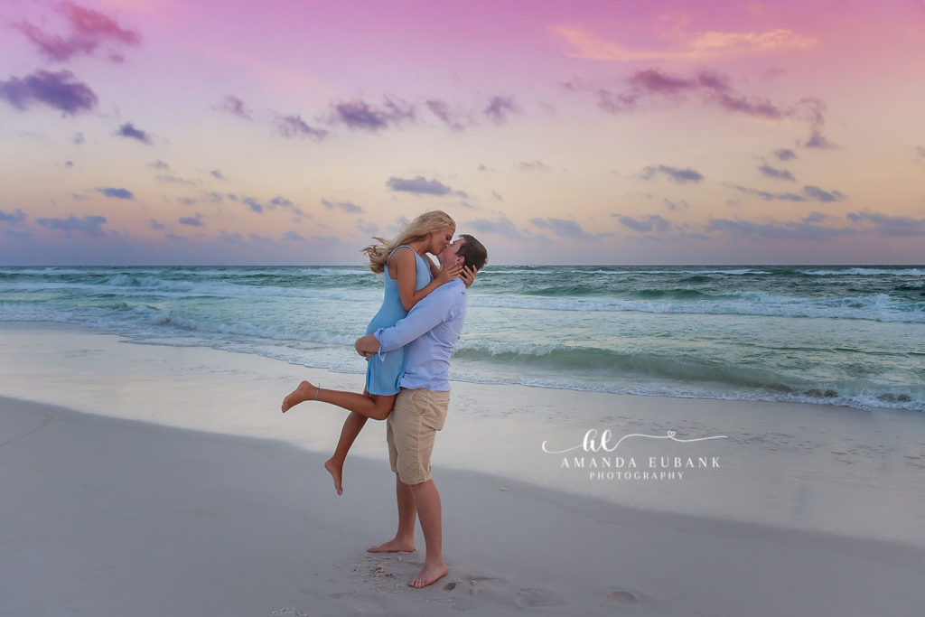 Newly engaged couple sharing a kiss on the beach after the surprise proposal