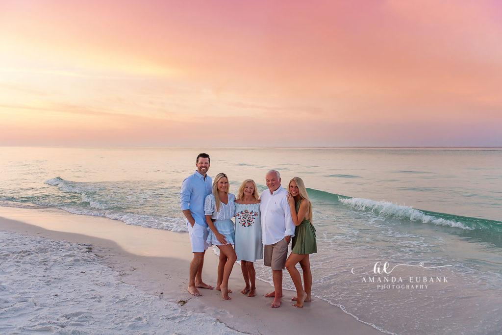 Wide family portrait of the Tuckers framed by Miramar Beach's emerald gulf