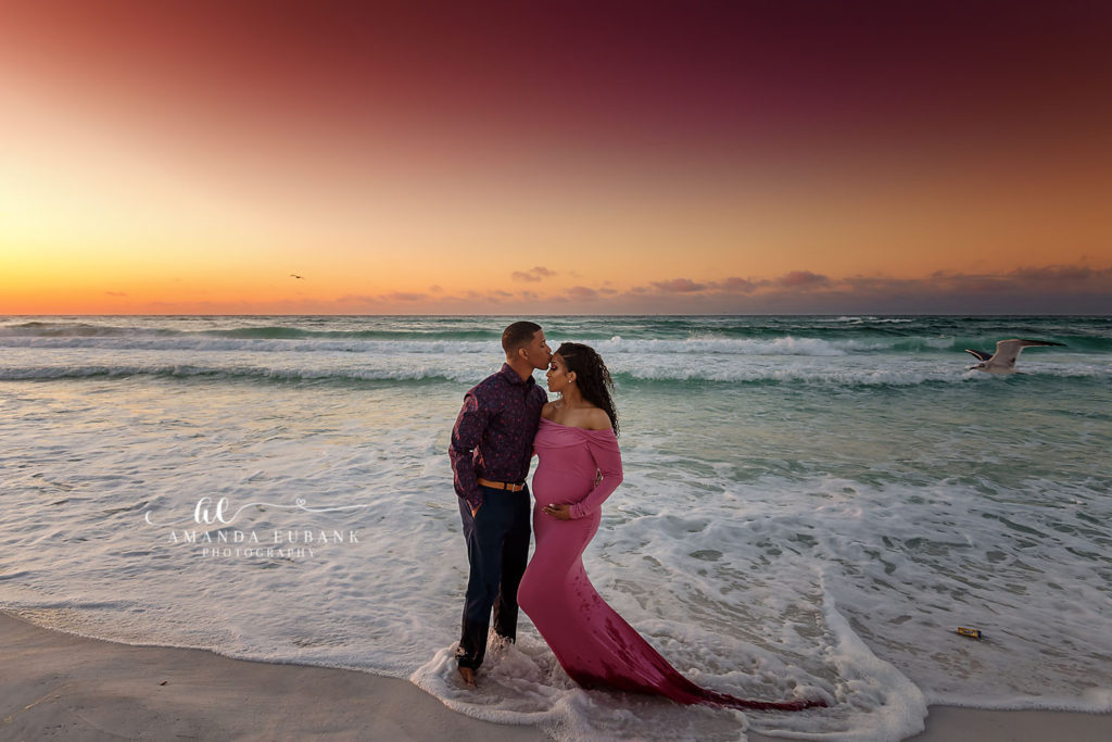 Wide coastal frame of Lynntrice's flowing dress matching the painted sunrise skies