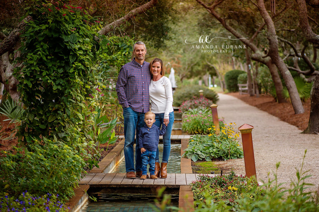 Mom and dad with their son framed by manicured greenery during their Watercolor garden session