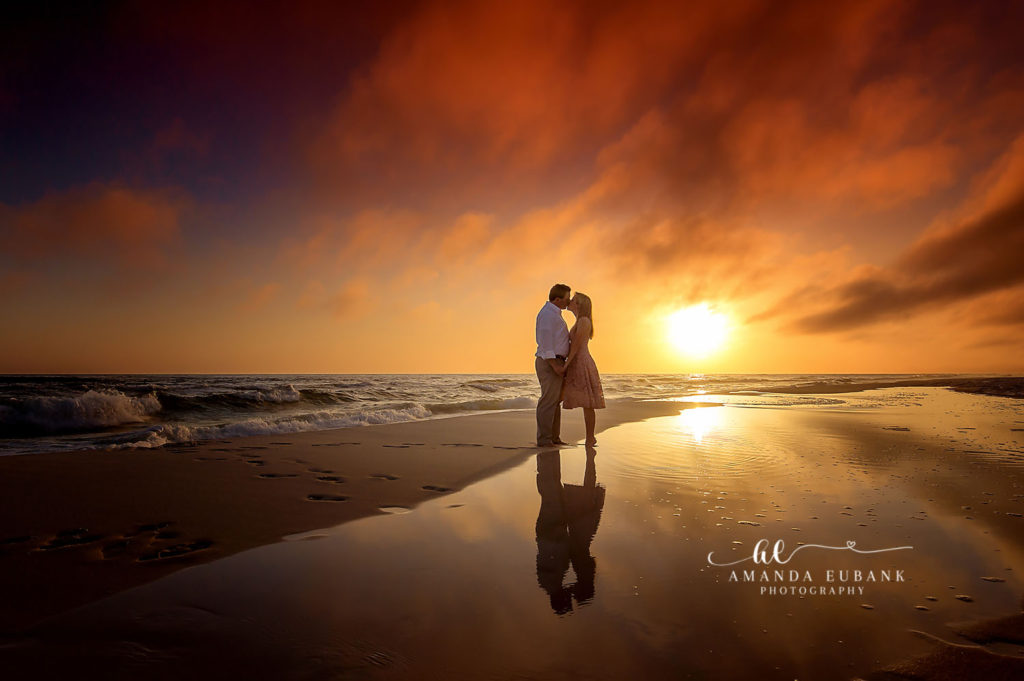 Soft painted-dune evening frame of Kara and Chris walking the shoreline