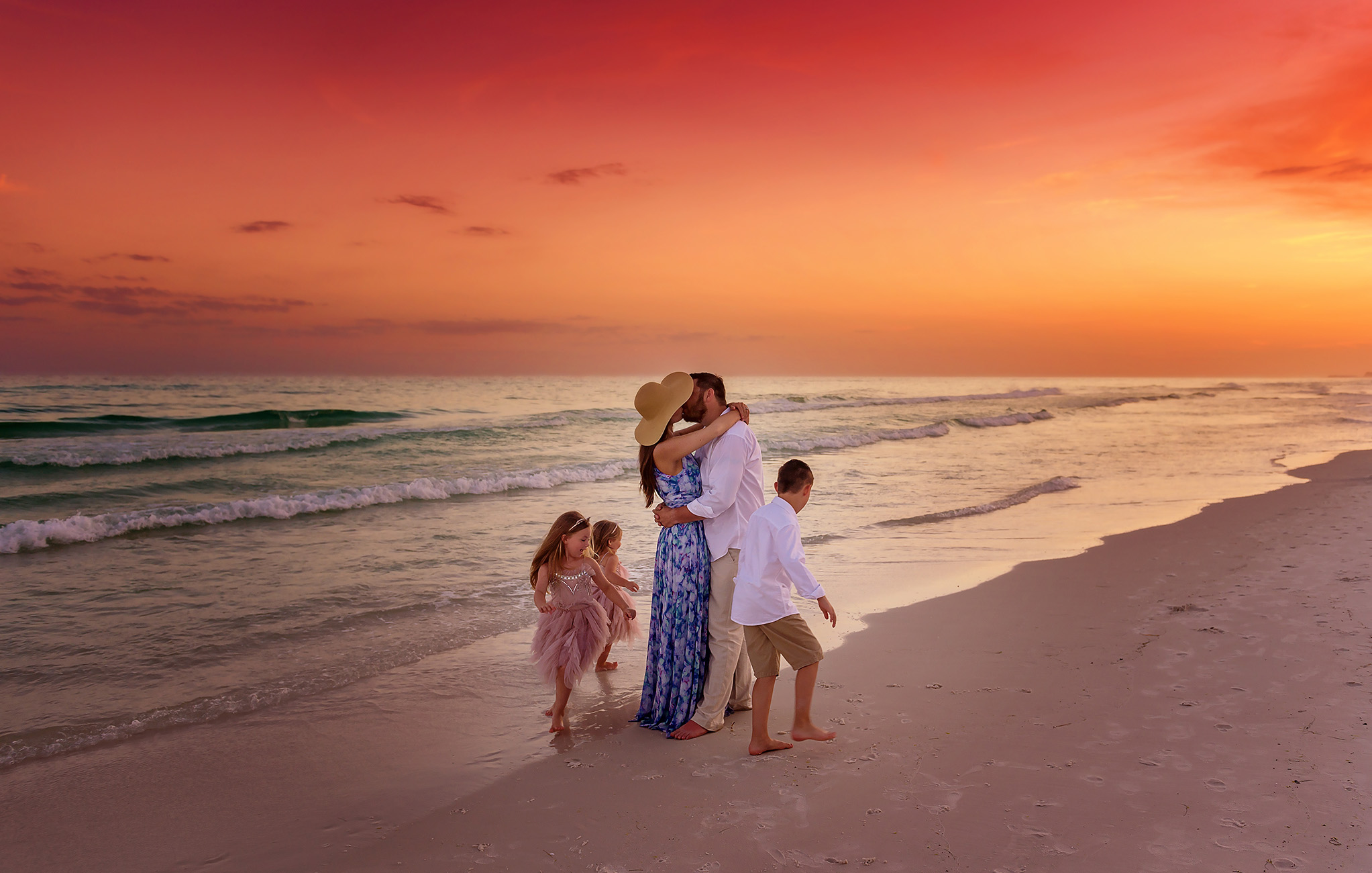 A family of seven walking together on Santa Rosa Beach at sunset with a vibrant orange and pink sky.