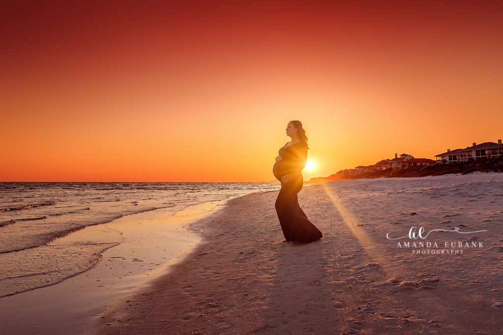 Playful candid of Amy and Sid walking barefoot along the Gulf shoreline at their maternity session