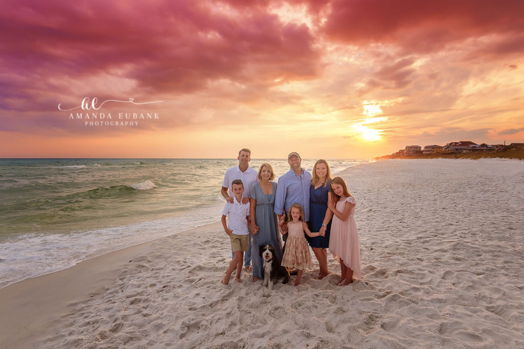 Jones extended family walking the Santa Rosa Beach shoreline with their dog beneath fiery sunset clouds