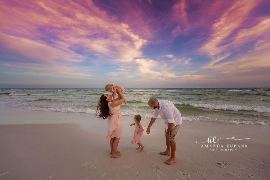 extended family reunion with multiple generations and young family at 30A sunset shoreline with glowing dusk, joyful sky-emphasized framing