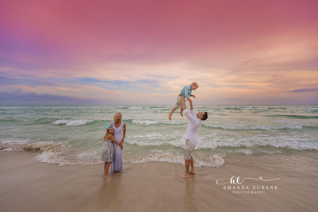 Tender parents-and-kids embrace at the shoreline as the Gulf glows behind them