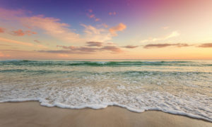 Foamy Gulf waves rolling onto sugar-white sand under a soft pink and peach sunset sky on Santa Rosa Beach along 30A in Florida.