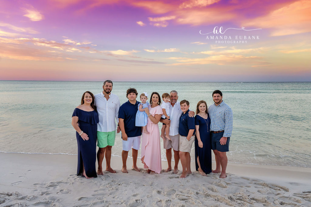 Big brother lifts his baby sister at the water's edge on Carillon Beach at sunset