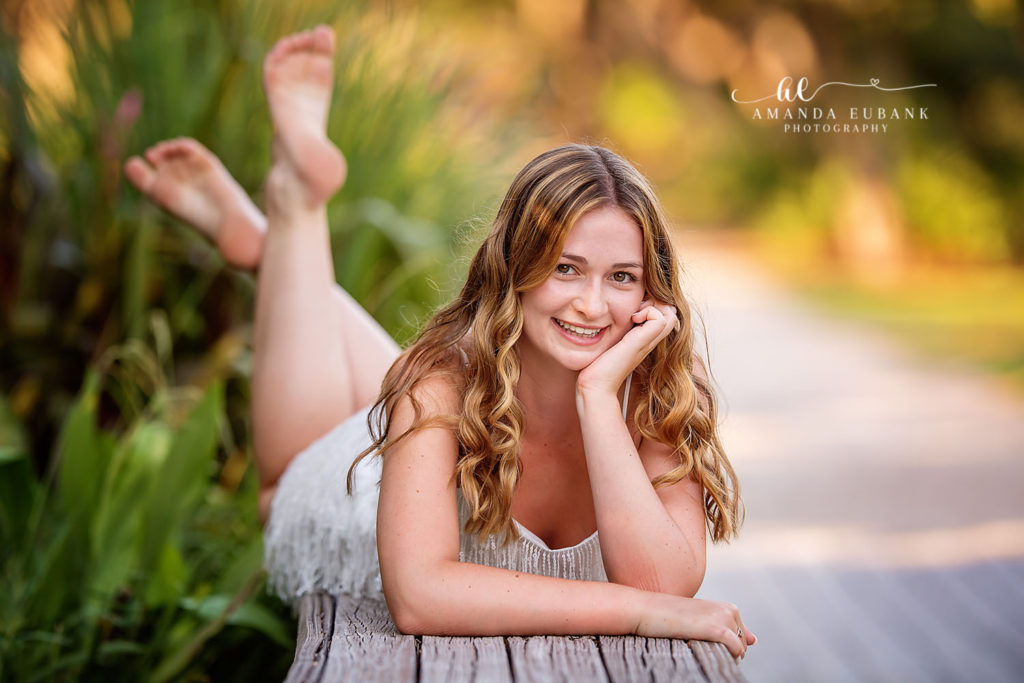 Senior Riley glances thoughtfully into the Watercolor gardens from the wooden bridge