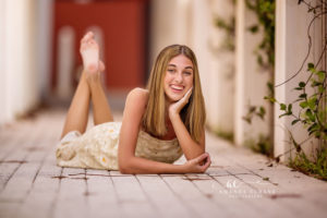Brunette senior Kaitlyn glances over her shoulder on pastel painted Rosemary Beach steps