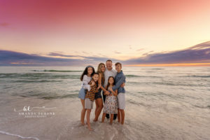 Affectionate Atkinson family group huddle on the Rosemary Beach sand at sunset.