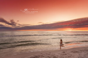 Quiet Atkinson family pose along the surf with light bouncing off the wet sand at sunset.