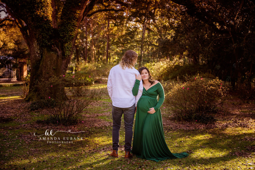 Zoi smiling at Matt under the live oaks during their maternity session at Eden Gardens.