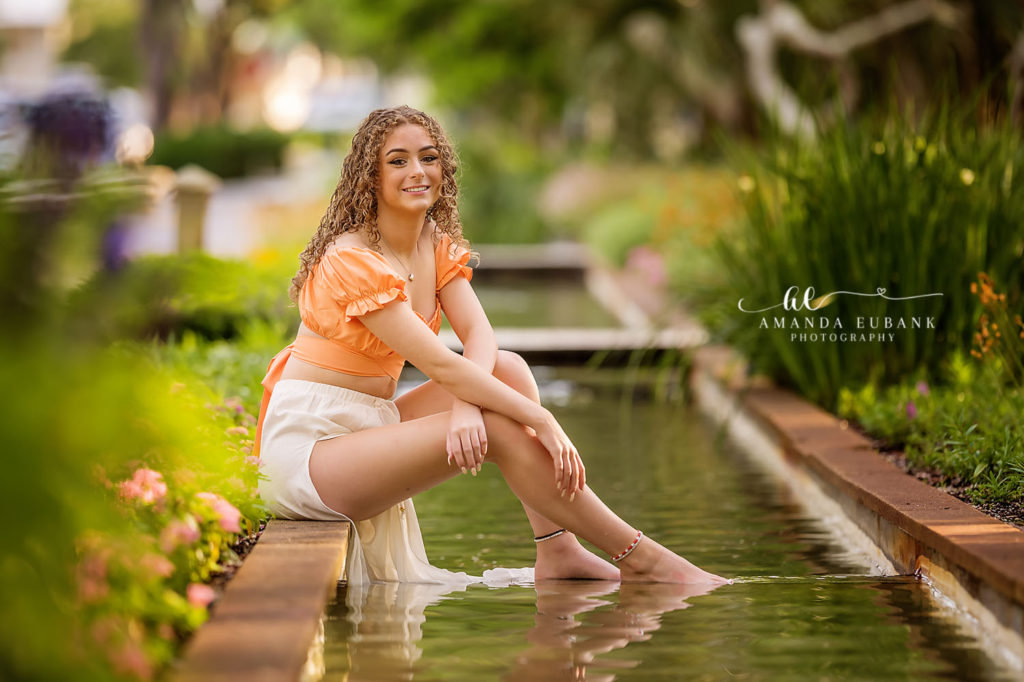 Candid laugh from Erin in an orange off-shoulder top during a Watercolor sherbet dusk.