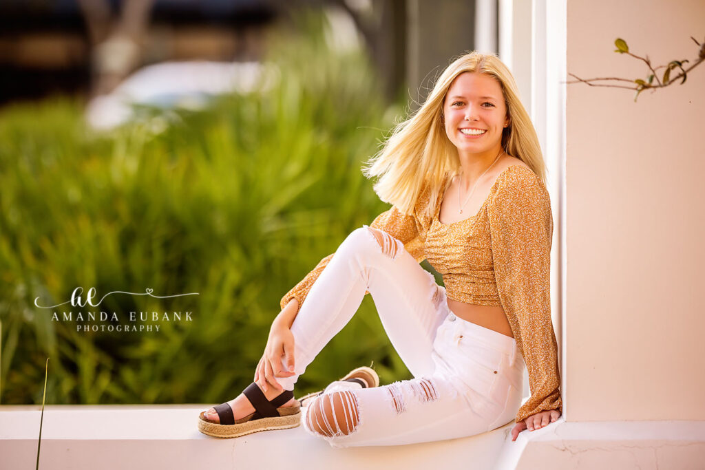 Hayley seated on a Rosemary Beach porch step in a leopard-print tank and white distressed jeans.