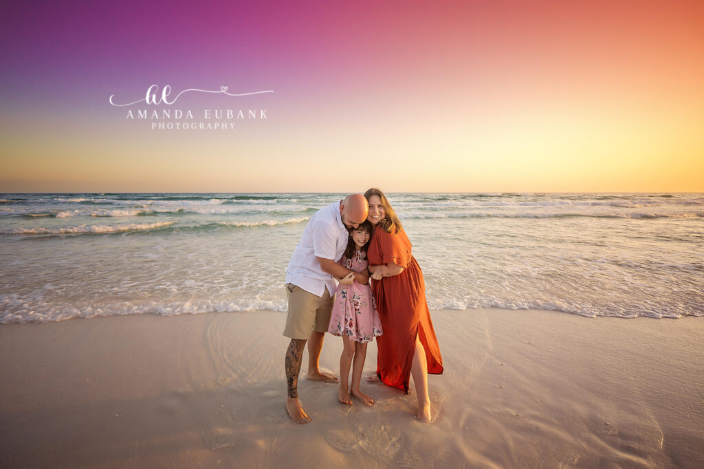 L family parents lifting their daughter playfully during their 30A beach session at sunset.