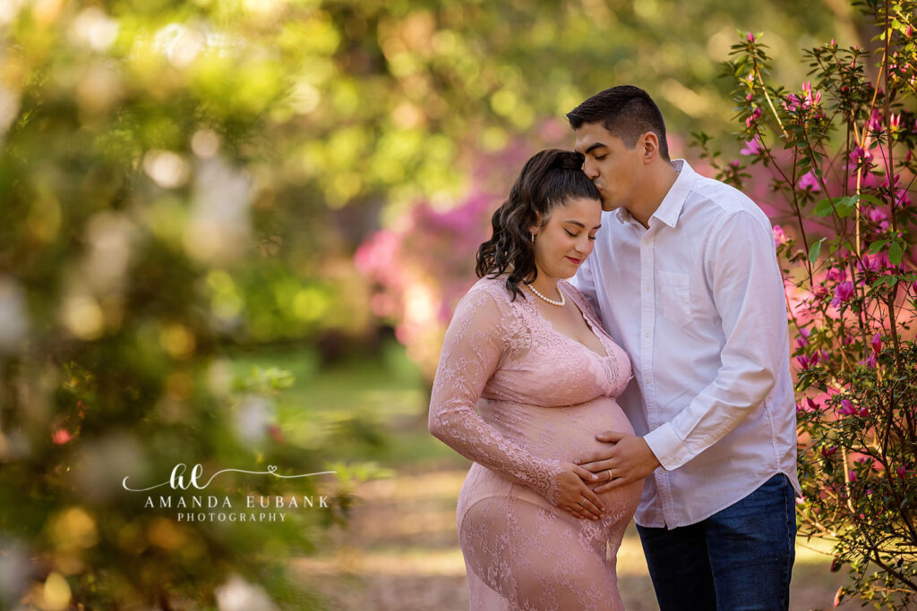 Expecting couple C + T connecting forehead to forehead in the Eden Gardens oak grove
