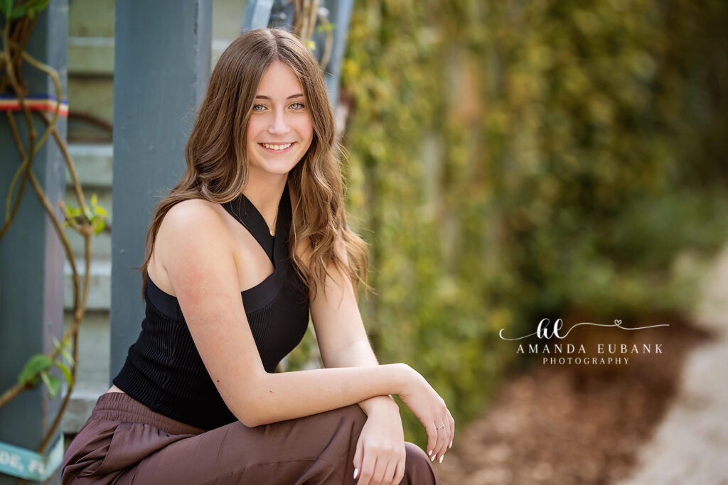 Molly seated on a canopy garden path during her Seaside and Watercolor senior session.