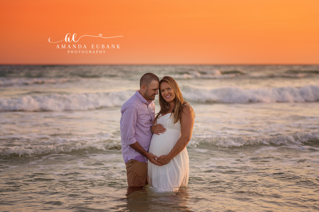 Expectant couple dad-to-be cradling the bump along Inlet Beach's white sand at rose-gold dusk.