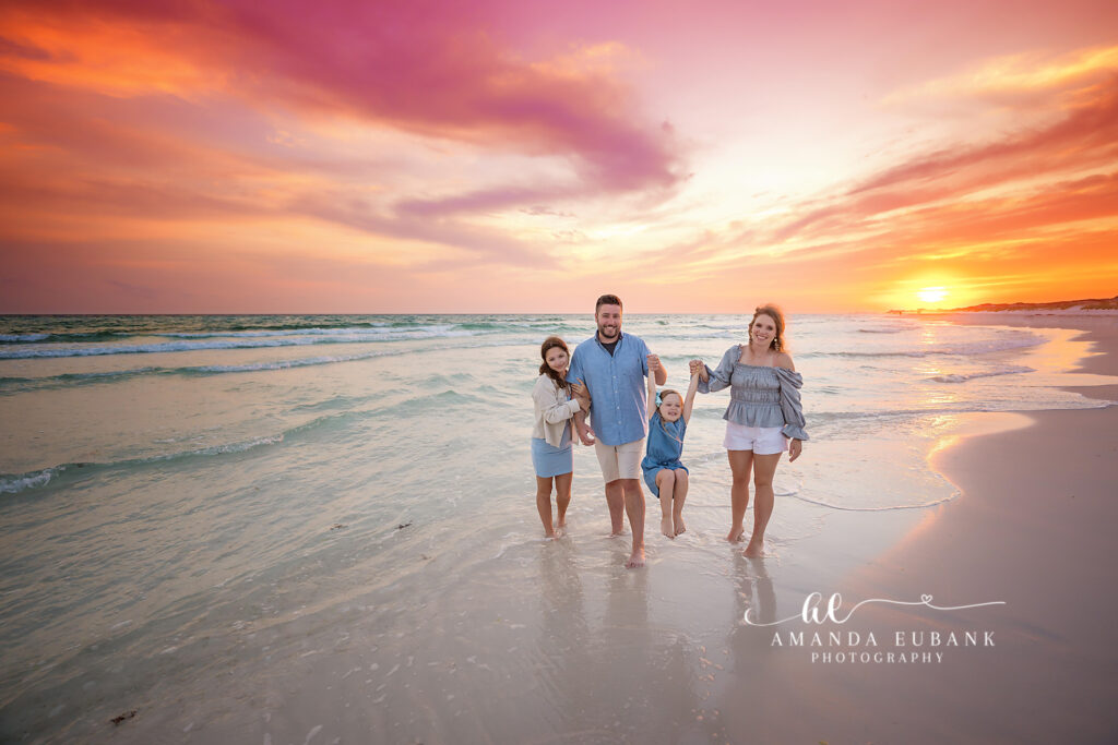 A multi-generational extended family pose on the powdery sand near the dune line during dreamy pastel dusk at Watercolor, Florida.