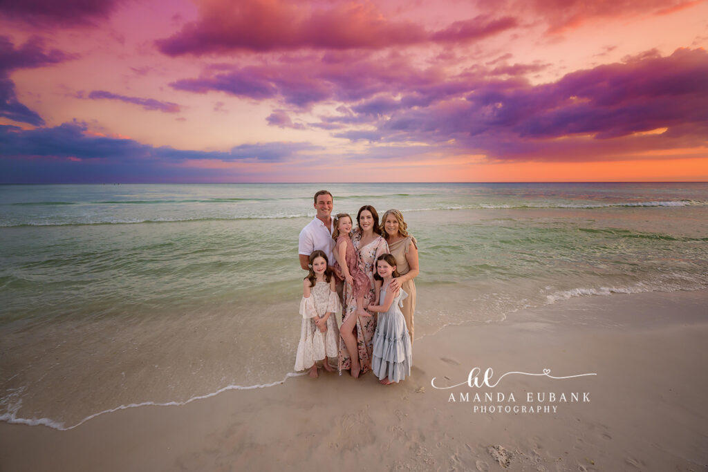 Mom holds her youngest while the older girls hug with the Gulf surf rolling in during blush and gold horizon.