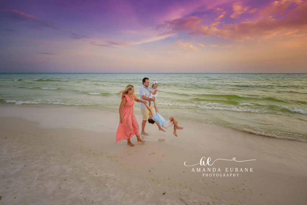 A candid family moment by the Gulf in the gentle Gulf surf at sunset during painted sunset sky.