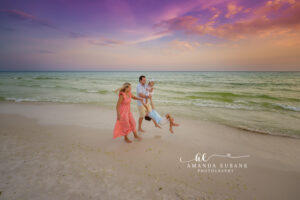 A candid family moment by the Gulf in the gentle Gulf surf at sunset during painted sunset sky.