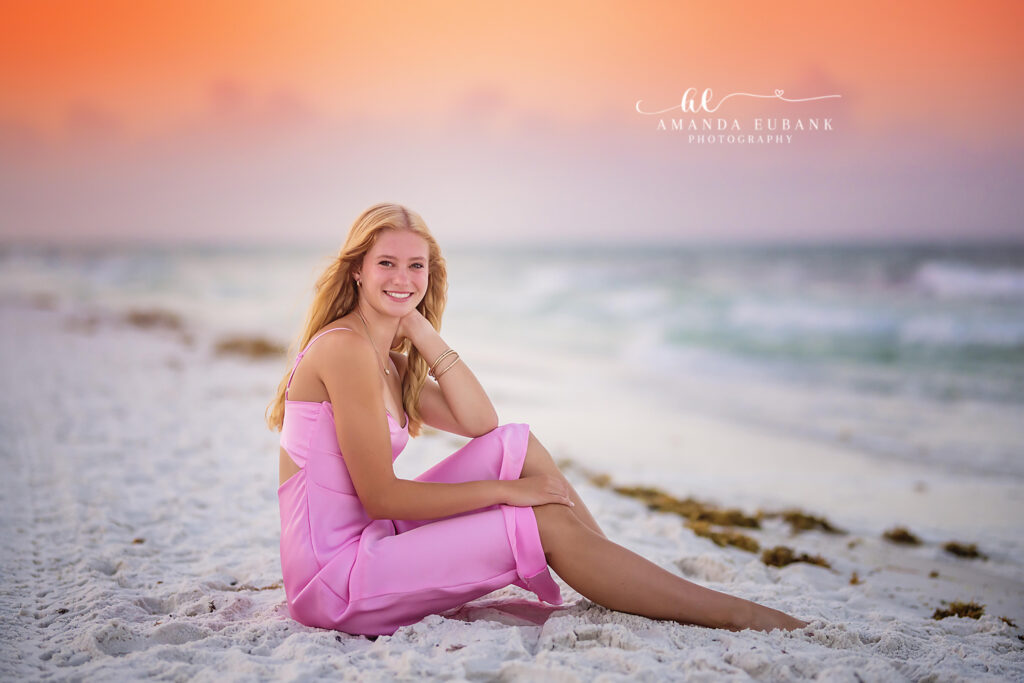 A senior portrait at sunrise on Seaside's shoreline with the Gulf surf rolling in behind her during radiant sunrise light.