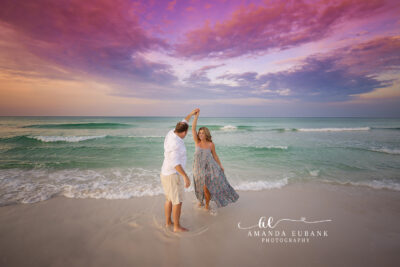 Seaside Sunrise Couple Session 14 A standing couple pose with sunrise sky behind them with the horizon glowing peach and rose during crisp morning light.