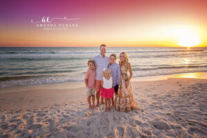 Mom embracing her son closely in soft pastel sunset light on the Emerald Coast shoreline.