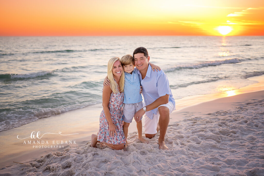 Radding dad holding his young son in the soft sunset light in coordinated blue collared shirts on the Seaside beach.