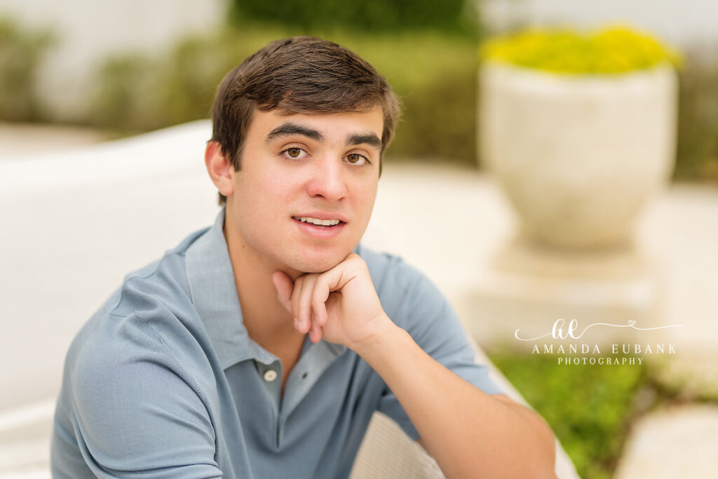 Jake standing on a manicured Alys Beach lawn in a crisp white linen shirt and khaki shorts surrounded by the signature white architecture.