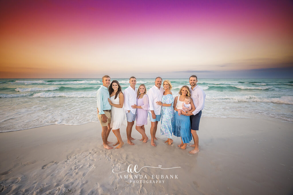 Three Dodson sisters playing with their baby niece in the gentle surf in sundresses and a tiny floral romper during a Destin sunrise session.