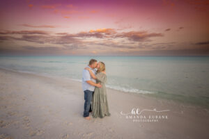 Daughter spinning joyfully in her teal floral dress on the open Miramar Beach sand beneath a pink-tinged twilight sky