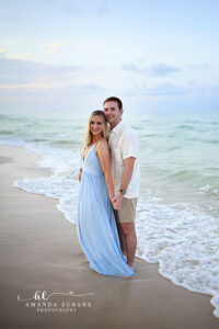 Newly engaged couple holding hands at the edge of the surf at Santa Rosa Beach with the bride in a powder-blue chiffon gown